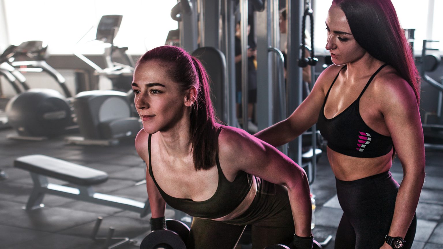 A trainer supporting a member during a strength session